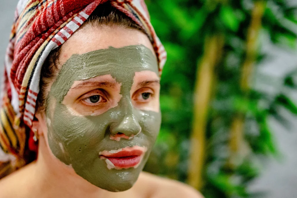 Kobieta relaksuje się podczas zabiegu z maseczką błotną na twarzy w spa.